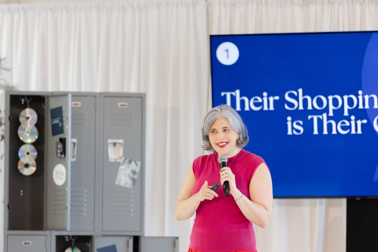 Wedding industry expert Meghan Ely speaking on stage with a microphone at a conference
