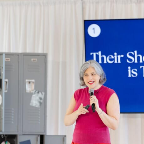 Wedding industry expert Meghan Ely speaking on stage with a microphone at a conference